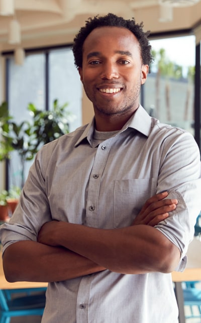 Smiling man with arms crossed in office.